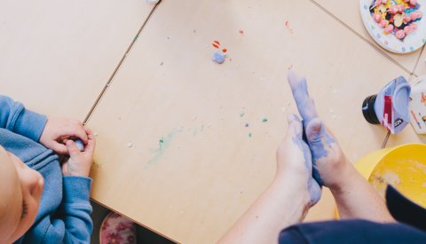 enfant et éducatrice jouant avec de la plasticine