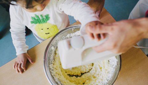 enfant aidant une éducatrice à faire de la pâtisserie